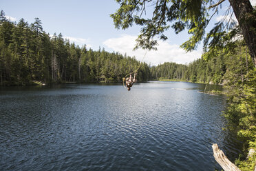 Unbekümmerter Mann springt von der Seilschaukel in den See - CAVF27419