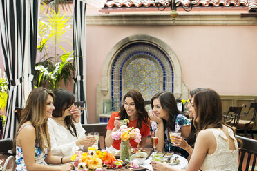 Fröhliche Frauen unterhalten sich in einem Restaurant im Freien - CAVF27435