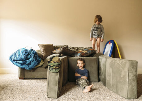 Porträt eines Jungen, der sich entspannt, während sein Bruder auf dem Sofa steht - CAVF27491