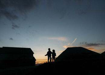 Silhouette boys standing on roof against sky - CAVF27496