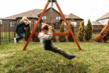 Jungen spielen auf Schaukeln im Hof - CAVF27500