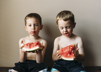 Porträt eines Jungen, der mit seinem Bruder zu Hause eine Wassermelone isst - CAVF27502