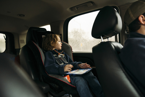 Junge schaut durch das Fenster, während er im Auto sitzt, lizenzfreies Stockfoto
