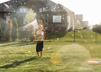 Boy squirting through water gun at backyard - CAVF27518