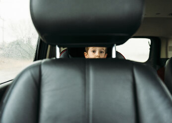 Portrait of boy looking through vehicle seat - CAVF27521