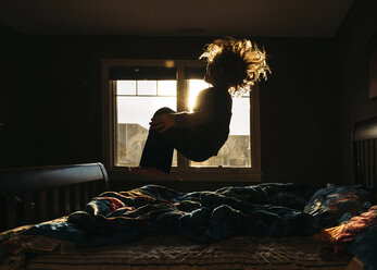 Playful boy jumping on bed at home - CAVF27539