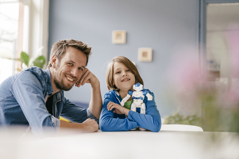 Portrait of happy father and son with robot at home stock photo