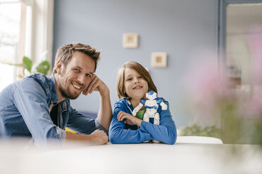 Portrait of happy father and son with robot at home - KNSF03582