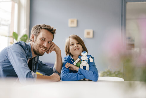Porträt eines glücklichen Vaters und eines Sohnes mit Roboter zu Hause - KNSF03582