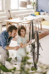 Father and son repairing bicycle together at home - KNSF03586