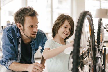 Father and son repairing bicycle together at home - KNSF03587