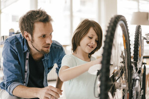 Vater und Sohn reparieren gemeinsam ein Fahrrad zu Hause - KNSF03587