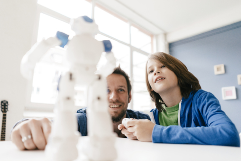 Vater und Sohn betrachten den Roboter auf dem Tisch zu Hause, lizenzfreies Stockfoto