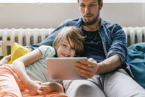 Vater und Sohn sehen sich zu Hause einen Film auf dem Tablet an - KNSF03606