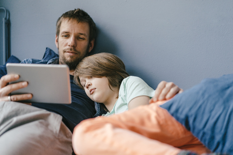Father and son watching a movie on tablet at home stock photo