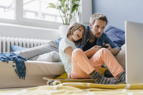 Father and son playing video game together at home stock photo