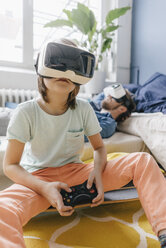 Boy and father wearing VR glasses playing video game at home - KNSF03614