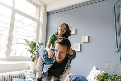 Happy father carrying son piggyback at home stock photo