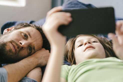 Father and son looking at smartphone together at home - KNSF03632