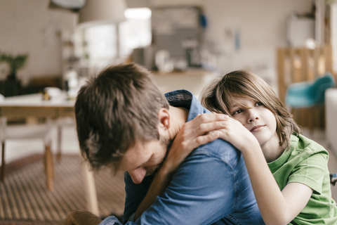 Sohn tröstet traurigen Vater zu Hause, lizenzfreies Stockfoto