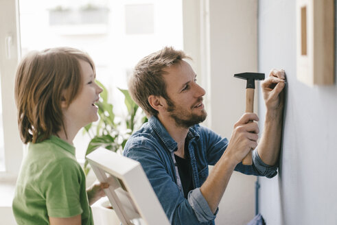 Sohn sieht zu, wie sein Vater zu Hause einen Nagel in die Wand schlägt - KNSF03641