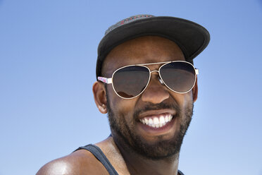 Low angle portrait of happy man wearing sunglasses against clear blue sky - CAVF27547