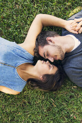 Draufsicht auf ein romantisches Paar, das im Gras liegt - CAVF27556