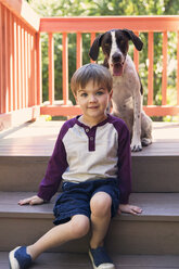 Porträt eines auf den Stufen sitzenden Jungen mit Hund - CAVF27563