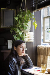 Thoughtful young woman looking through window at home - CAVF27573