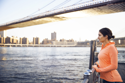 Seitenansicht einer Sportlerin mit Blick auf die Stadt von der Promenade aus, lizenzfreies Stockfoto