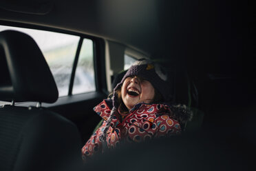 Cheerful girl laughing while sitting in car - CAVF27612