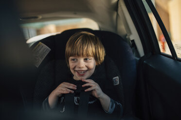 Happy boy looking away while sitting in car - CAVF27613