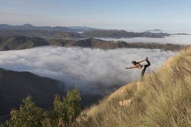 Frau übt Yoga auf Berg gegen Himmel in nebligem Wetter - CAVF27654