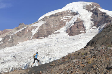 Female backpacker walking on mountain against sky - CAVF27661