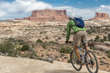 Rear view of man riding bicycle on mountain against sky - CAVF27683