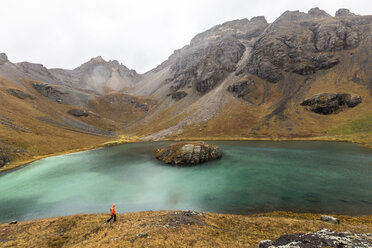 Mann spaziert am See gegen Berge - CAVF27686