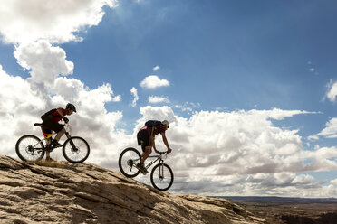 Seitenansicht von Mountainbikern auf Fahrrädern gegen bewölkten Himmel - CAVF27695
