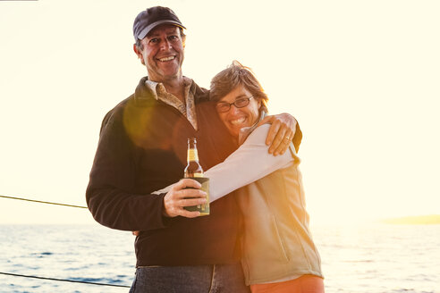 Porträt eines lächelnden Paares, das sich umarmt, während es auf einem Boot gegen den klaren Himmel steht - CAVF27706
