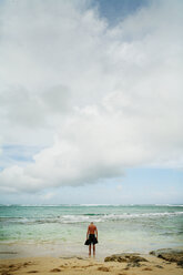 Full length of man standing on seashore against cloudy sky - CAVF27711