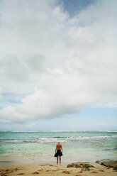 Mann in voller Länge am Meeresufer stehend gegen bewölkten Himmel - CAVF27711