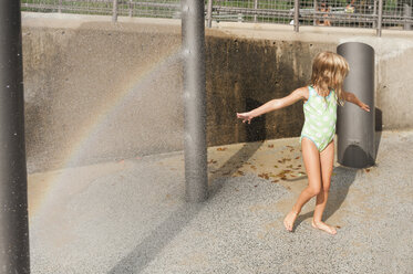 Verspieltes Mädchen genießt den Sommerurlaub in einem Springbrunnen an einem sonnigen Tag - CAVF27712