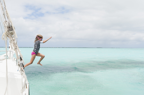 Volle Länge des Mädchens Tauchen im Meer von Boot gegen bewölkten Himmel, lizenzfreies Stockfoto