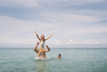 Father enjoying with daughters in sea against cloudy sky - CAVF27726