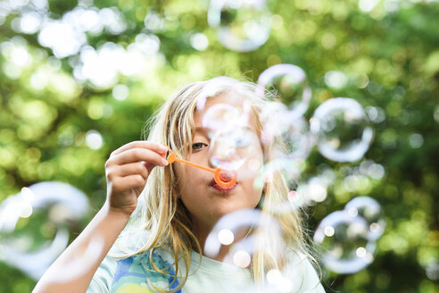 Girl blowing bubbles at park - CAVF27739