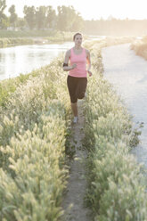 Sportswoman jogging amidst plants in park - CAVF27755