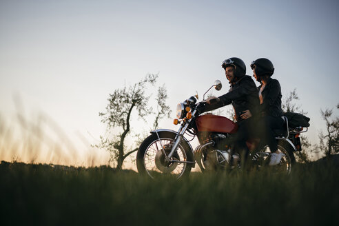 Niedriger Blickwinkel auf ein junges Paar auf einem Motorrad gegen den klaren Himmel - CAVF27777