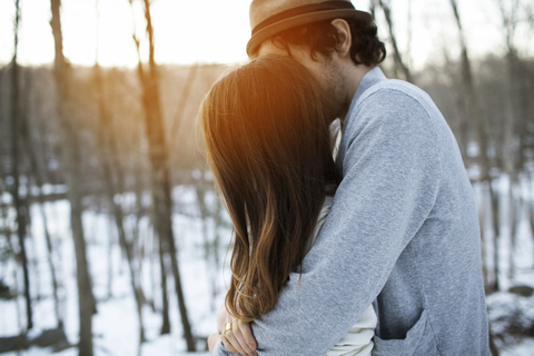 Seitenansicht eines sich umarmenden Paares im Winter, lizenzfreies Stockfoto