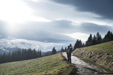 Mann und Frau stehen auf einem Berg vor bewölktem Himmel - CAVF27793