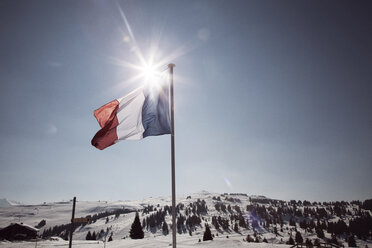 Französische Flagge auf schneebedecktem Feld gegen den Himmel an einem sonnigen Tag - CAVF27824