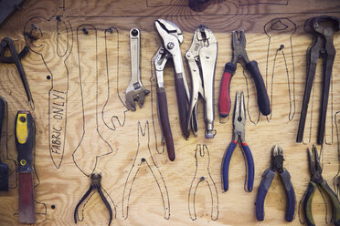 Werkzeuge hängen über Skizzen an der Holzwand - CAVF27843